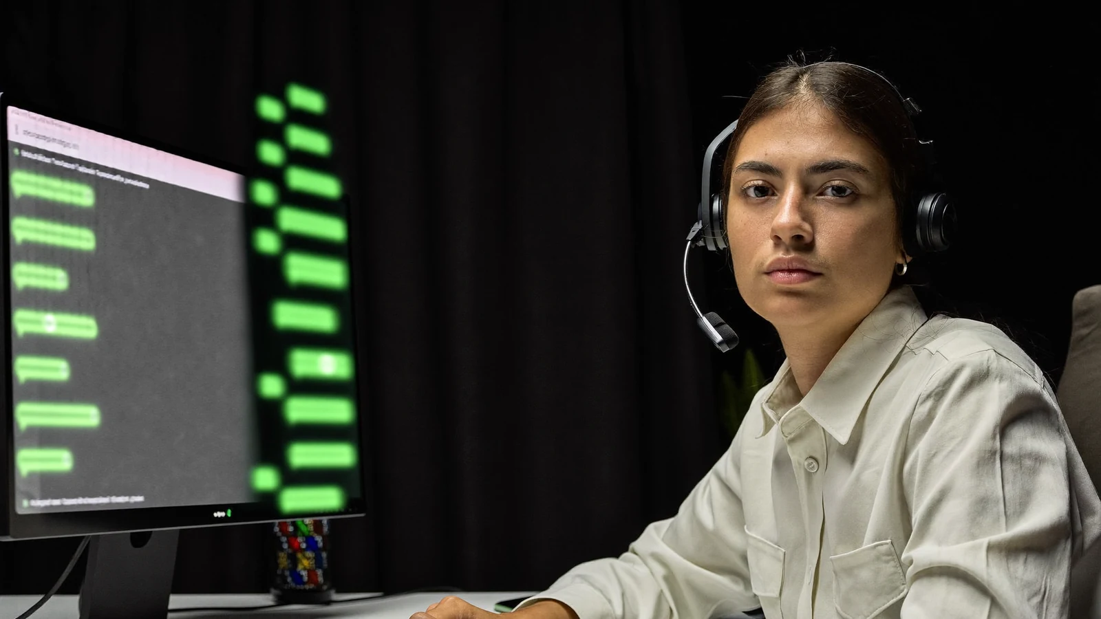 Atendente de SAC com headset acompanhando uma fila de conversas de clientes na tela do computador