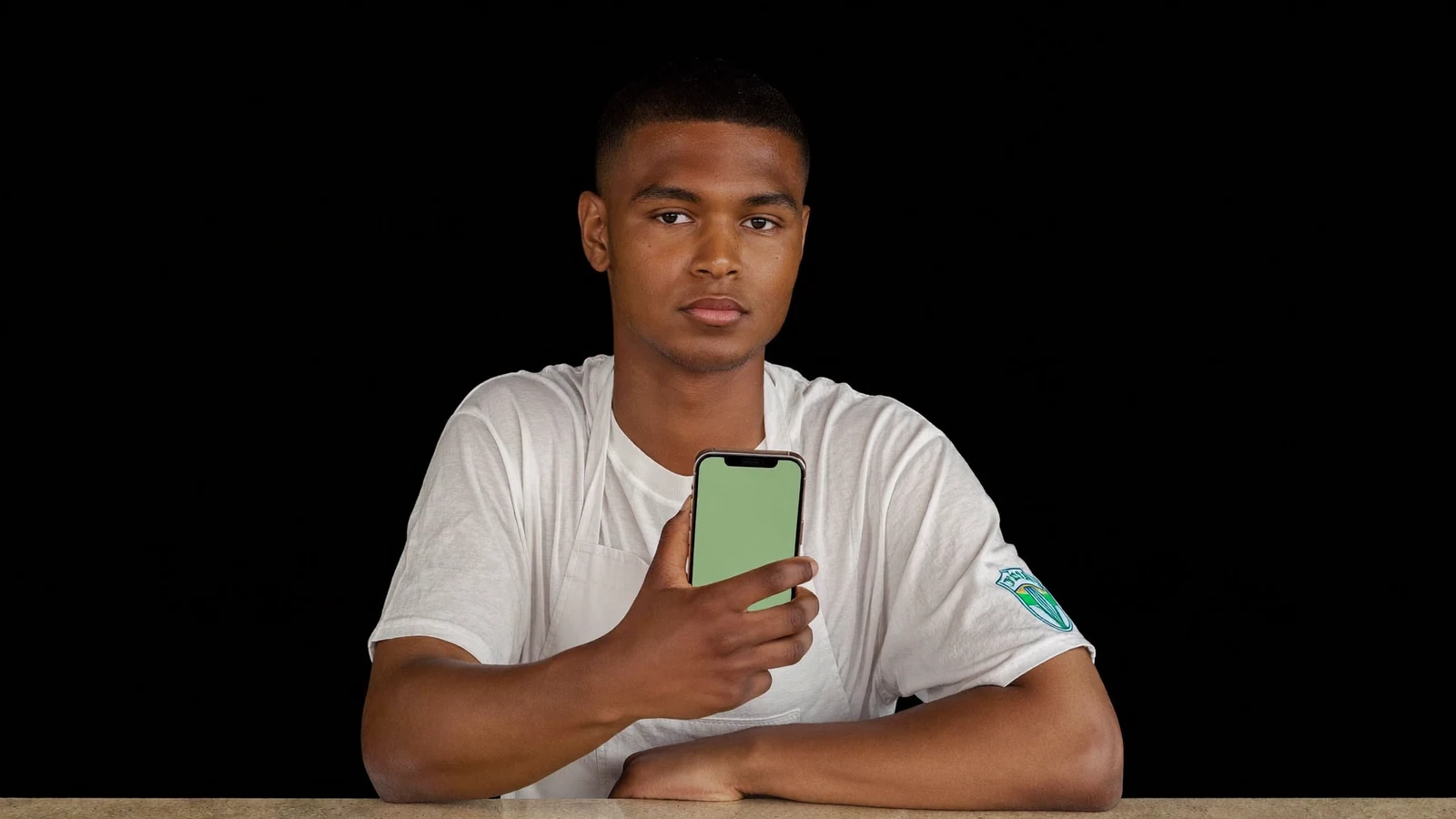Jovem lojista sentado ao balcão segurando o celular com a tela do aplicativo acesa