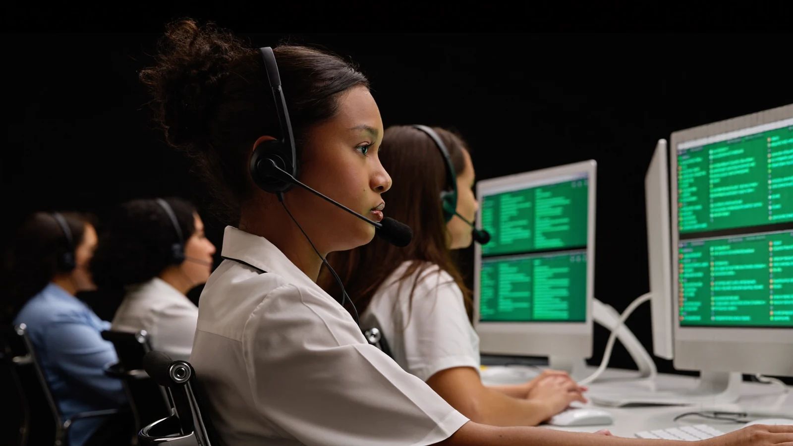 Equipe de quatro atendentes com headset trabalhando lado a lado em uma central de atendimento